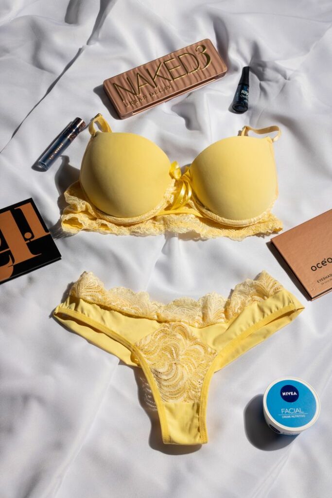 Flat lay of yellow lingerie set with beauty products on a white background.